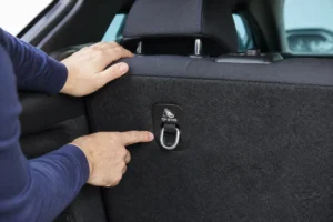 Gros plan sur une main inspectant l'anneau métallique d'ancrage Isofix pour savoir si la voiture est compatible.
